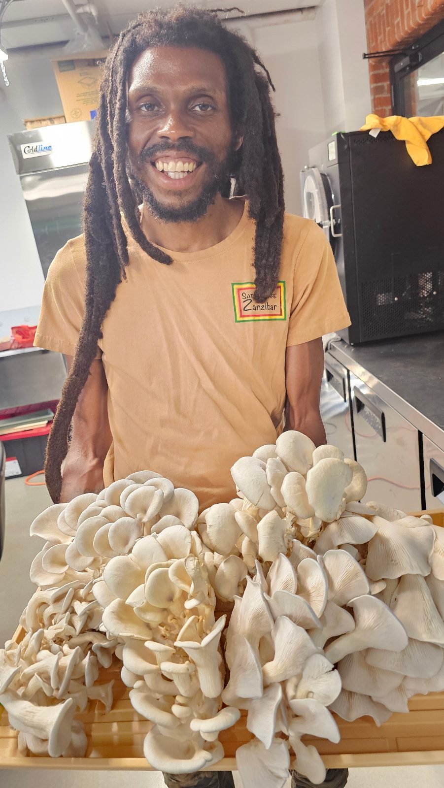 A Root Life grower holding a tray of freshly harvested oyster mushrooms